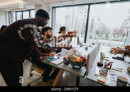 A dynamic image capturing a diverse group of professionals actively participating in a business meeting at a brightly-lit office. Stock Photo