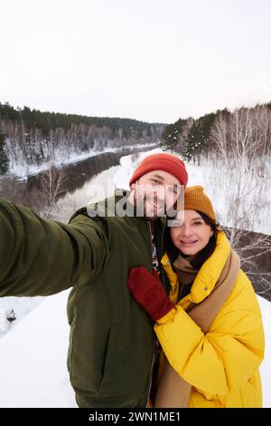 POV of cheerful Caucasian man and woman in love taking selfie on smartphone on frosty winter day Stock Photo