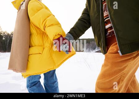 Medium section shot of unrecognizable young man and woman in love holding hands hiking on winter day Stock Photo