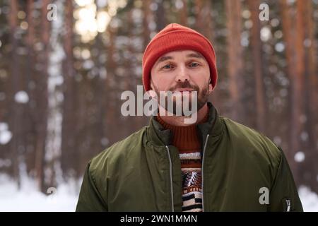 Portrait of young Caucasian man wearing warm clothes standing in forest on winter day Stock Photo