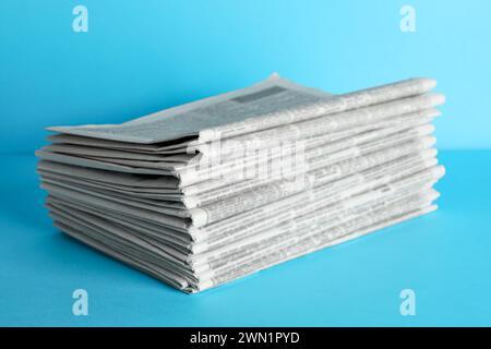 Stack of newspapers on light blue background. Journalist's work Stock Photo