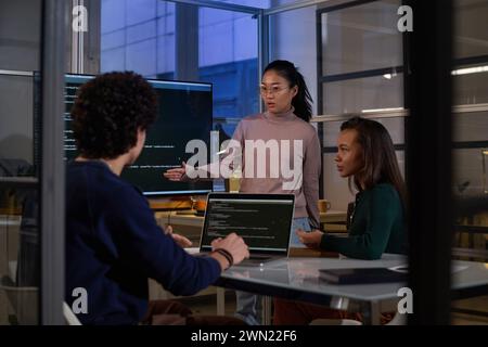 Ethnically diverse programmers working together on code at workplace in IT company office late in evening Stock Photo