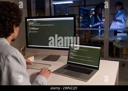 Unrecognizable male programmer developing code typing on computer late in evening, copy space Stock Photo