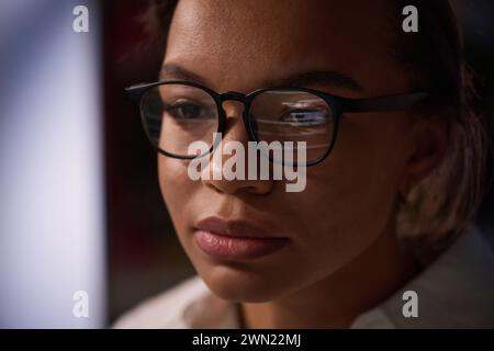 Closeup shot of young female programmer wearing eyeglasses working on code in IT company office late at night Stock Photo