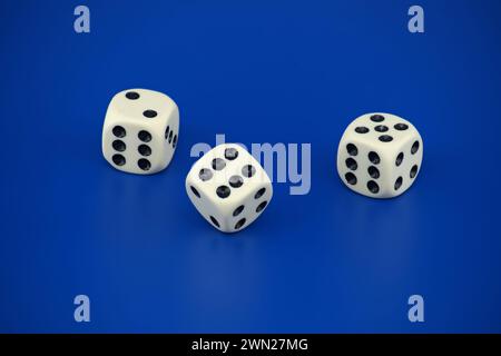 Gaming scenario scene with three dice with black spots situated on a blue background Stock Photo