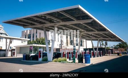 A Tesla Supercharger charging station or charge point beneath large solar panels for charging electric cars in Santa Monica, California, United States Stock Photo