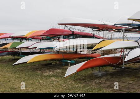 Many different colorful sea kayaks stored in a rack on land during winter Stock Photo