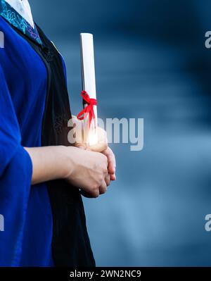 Detail of female student in gown holding a diploma Stock Photo