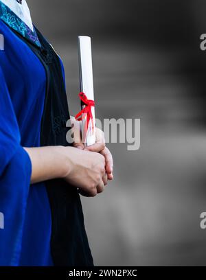 Detail of female student in gown holding a diploma Stock Photo
