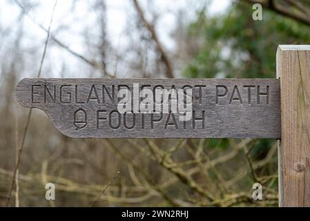 Wooden England coast path sign pointing left in the direction of the footpath.  February 2024. Stock Photo