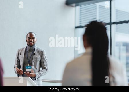 Happy male speaker presents to attentive colleagues at a professional business seminar in a bright, contemporary conference room setting, exemplifying Stock Photo