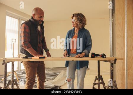 Couple collaborating on a home renovation project. They discuss, plan, and work together indoors. The husband and wife, both mature homeowners, focus Stock Photo