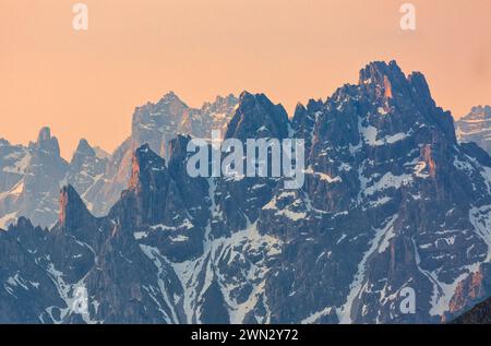 Snow-covered mountain range at sunset with clouds in the sky Stock Photo