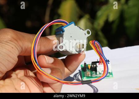 Stepper motor used in various hobby electronics projects held in the hand with stepper motor driver on the background Stock Photo