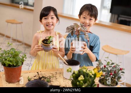 Cute children planting potted plant at home Stock Photo