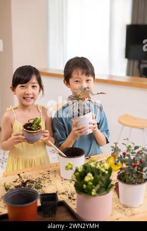 Cute children planting potted plant at home Stock Photo