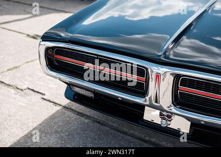 Front of black 1972 Dodge Charger. Close-up shot of muscle car with chrome trim, headlight covers and reflection of the sky in black bodywork Stock Photo