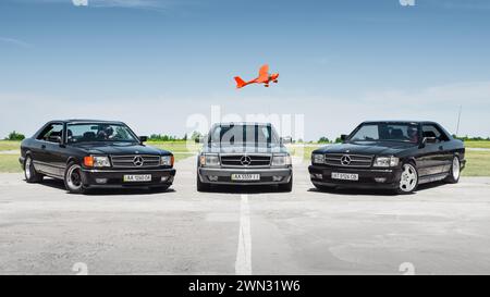 Mercedes-Benz SEC S-class coupes C126 (W126) model. 1980s Mercedes luxury coupes on a sunny day at airfield - ultralight Aeroprakt plane in background Stock Photo