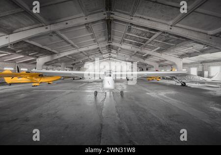 Small airplanes in storage at small aerodrome. Hangar of flying club with light aircraft - propeller driven ones and a glider. Stock Photo