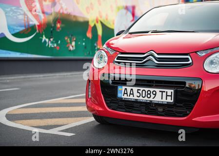 close up view of red Citroen C1: front bumper and headlight in focus and colorful wall in the background Stock Photo