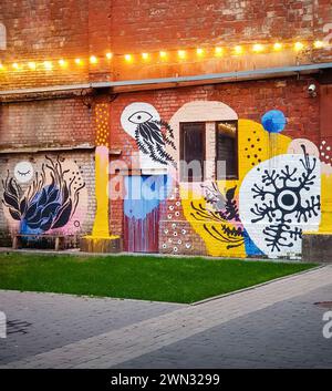 street art on the wall of old factory. brick factory facade with conceptual colorful painting on it Stock Photo