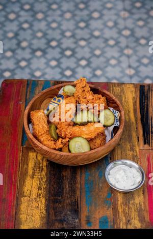 bowl of fried chicken with pickles with mayo on the side served on a wooden table Stock Photo