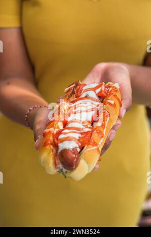 woman in a yellow dress holding a hotdog Stock Photo