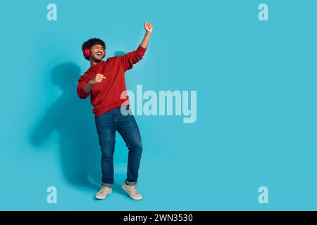Full length portrait of overjoyed person dancing listen favorite playlist empty space isolated on blue color background Stock Photo