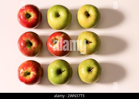 Nine apples arranged in a 3x3 grid on a light surface. A study in symmetry, color contrast, and natural texture with warm directional lighting. Stock Photo