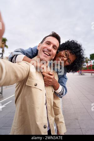 Happy middle-aged couple smiling at the camera while taking a selfie outdoors. Stock Photo