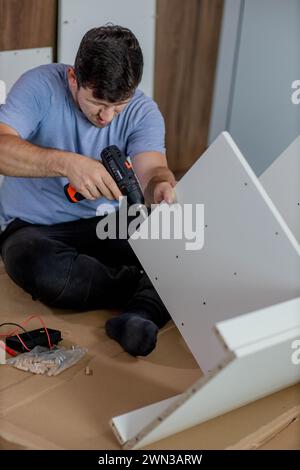 Man assembling furniture by using cordless screwdriver. Stock Photo