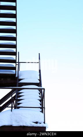 Stairway to heaven. Closeup of fire escape with snow against winter sky Stock Photo