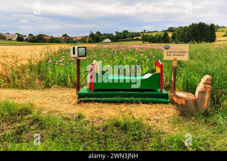 Colourful wooden bed outdoors, on straw, vintage TV, original hiking trail in the poppy field, sign with inscription, Please do not disturb, We sleep Stock Photo