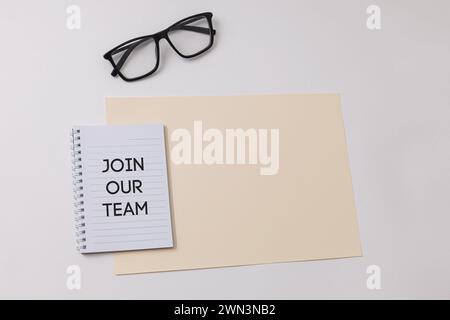 Notebook with Join our team text is on top of white office desk table with black glasses Stock Photo