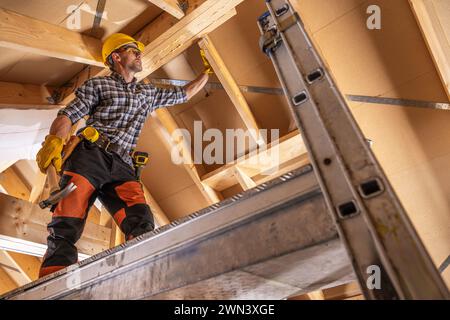 Construction Contractor Worker on a Scaffolding Performing Roof Elements Assembly Stock Photo