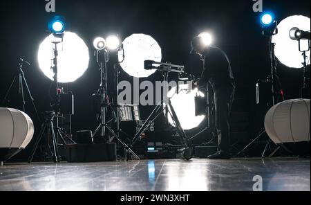 A Man Assembling Powerful Modern LED Video and Photo Lighting Inside Dark Production Studio Stock Photo