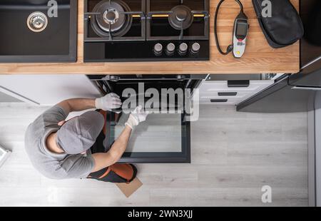 Professional Appliances Installer and Testing New Kitchen Stove. Top View. Kitchen Equipment Theme. Stock Photo