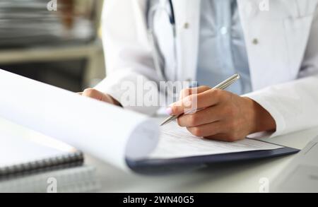 Hands of female GP making notes with silver pen Stock Photo