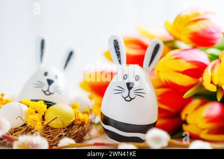 Augsburg, Bavaria, Germany - February 28, 2024: Easter bunny Easter egg next to tulips *** Osterhase Osterei neben Tulpen Stock Photo
