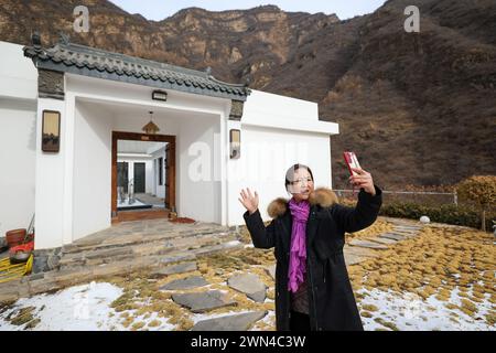 (240229) -- TIANJIN, Feb. 29, 2024 (Xinhua) -- A homestay manager takes a short video to promote her business in Qian'ganjian Village, Xiaying Township, north China's Tianjin, Feb. 23, 2024. Before this year's Spring Festival, three villages including Qian'ganjian Village of Tianjin, Qian'ganjian Village of Hebei Province and Hongshimen Village of Beijing, all located at a border area between Tianjin, Hebei and Beijing, signed an agreement to jointly develop the tourism in the area and better protect the ancient Great Wall.    As one of the three villages, Qian'ganjian Village of Tianjin has w Stock Photo