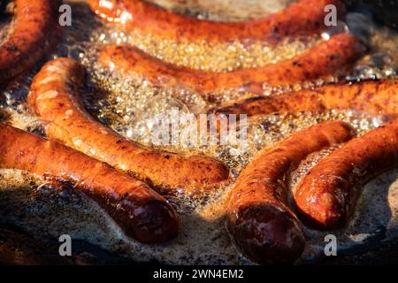 Street Food cooking on big frying pan, tasty home made sausages on large commercial griddle hotplate, food festival at country side of Serbia Stock Photo