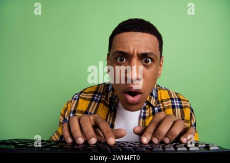 Portrait of speechless crazy person open mouth staring fingers typing keyboard isolated on green color background Stock Photo