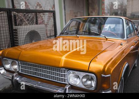Classic sports car parked on a urban street. Old orange American car close-up. Muscle Car headlights. Street photo, nobody Stock Photo