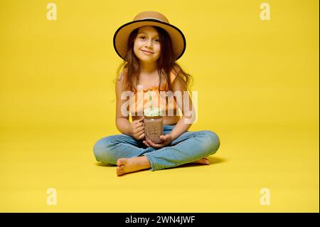 Portrait of an adorable cheerful little kid girl holding a freshly squeezed fruity juice, expressing positive emotions, smiling looking at the camera, Stock Photo