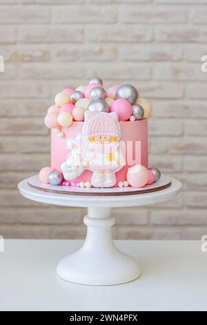 Cute gradient birthday cake with gingerbread little girl and bunny, with a pile of chocolate silver balls on the top. Ideal gift for a child Stock Photo