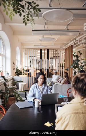 Businesswoman using laptop while working with colleagues at coworking office Stock Photo