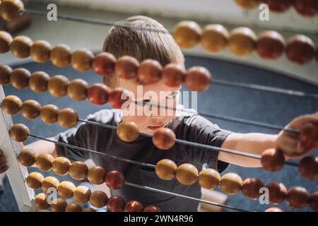 High angle view of boy leaning to count using abacus in classroom Stock Photo