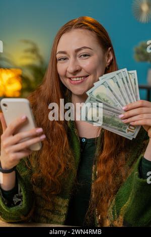 Planning budget. Rich happy redhead woman counting money cash use