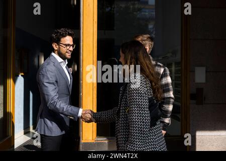Male real estate agent doing handshake with clients in front of apartment Stock Photo