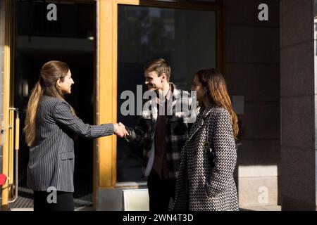 Happy couple shaking hand with female real estate agent in front of apartment Stock Photo